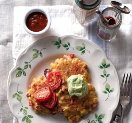 A plate of sweetcorn and chorizo fritters topped with tomatoes and avocado