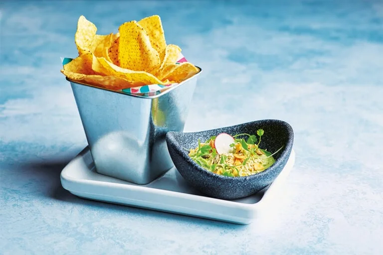 Bowl of Wahacamole and tin of tortilla chips