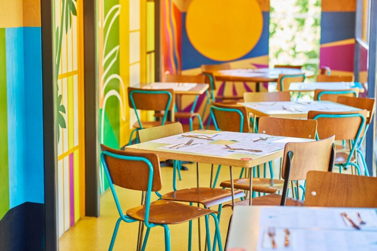 Colourful abstract wall murals at Wahaca Southbank with lots of small tables set for dining