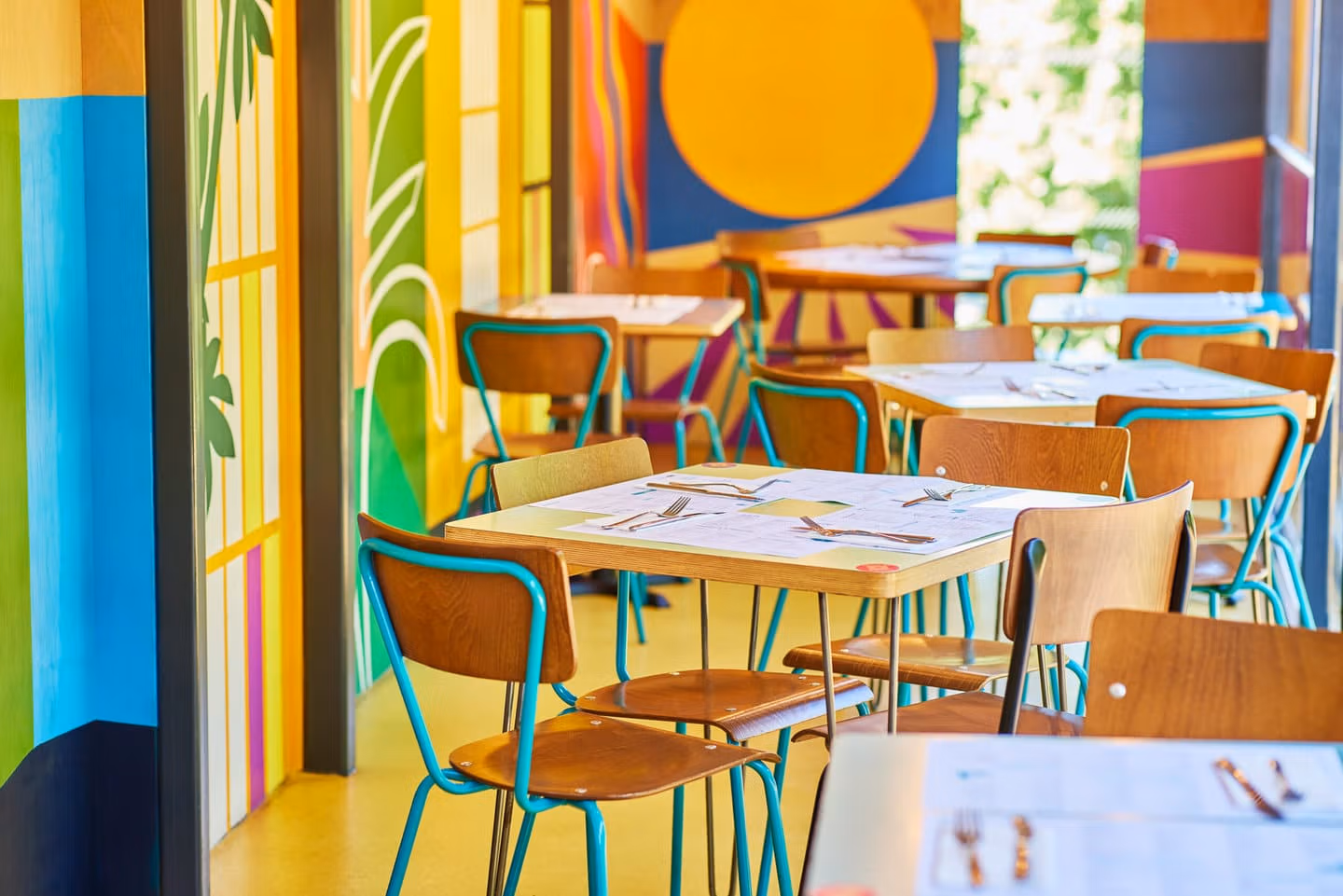 Colourful abstract wall murals at Wahaca Southbank with lots of small tables set for dining