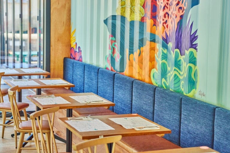 A colourful mural behind tables at Wahaca Southbank