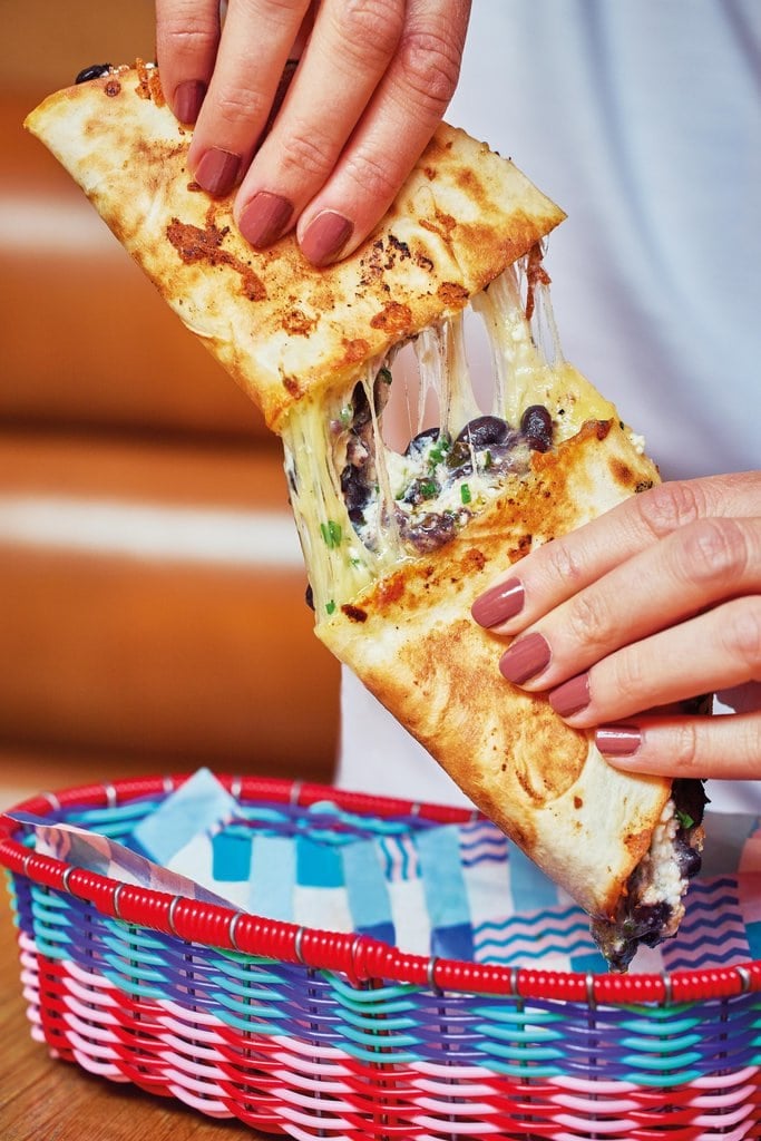 Black bean and cheese quesadilla being pulled apart to reveal a melted cheesy centre packed with beans