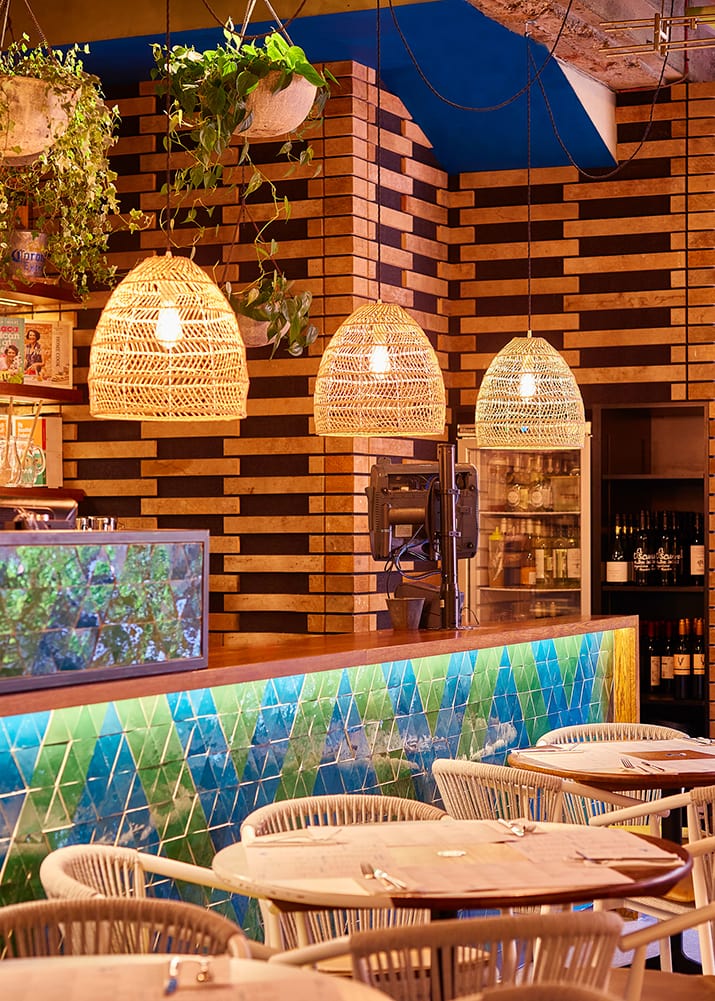 Warmly lit bar area at Wahaca Covent Garden with colourful tiles and hanging plants