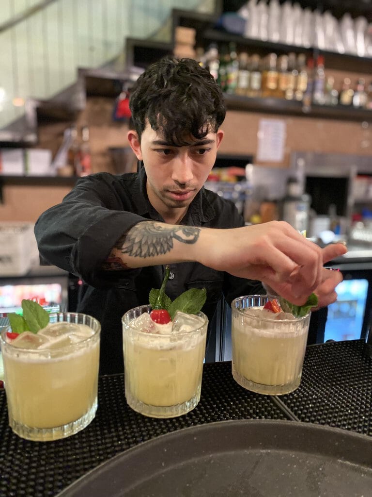 A bar person garnishing picante margaritas