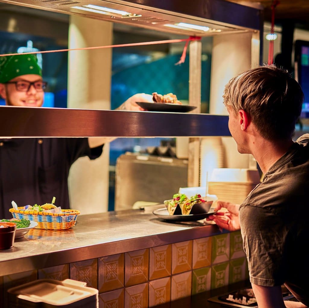 Waiter accepting a dish on the pass from a chef