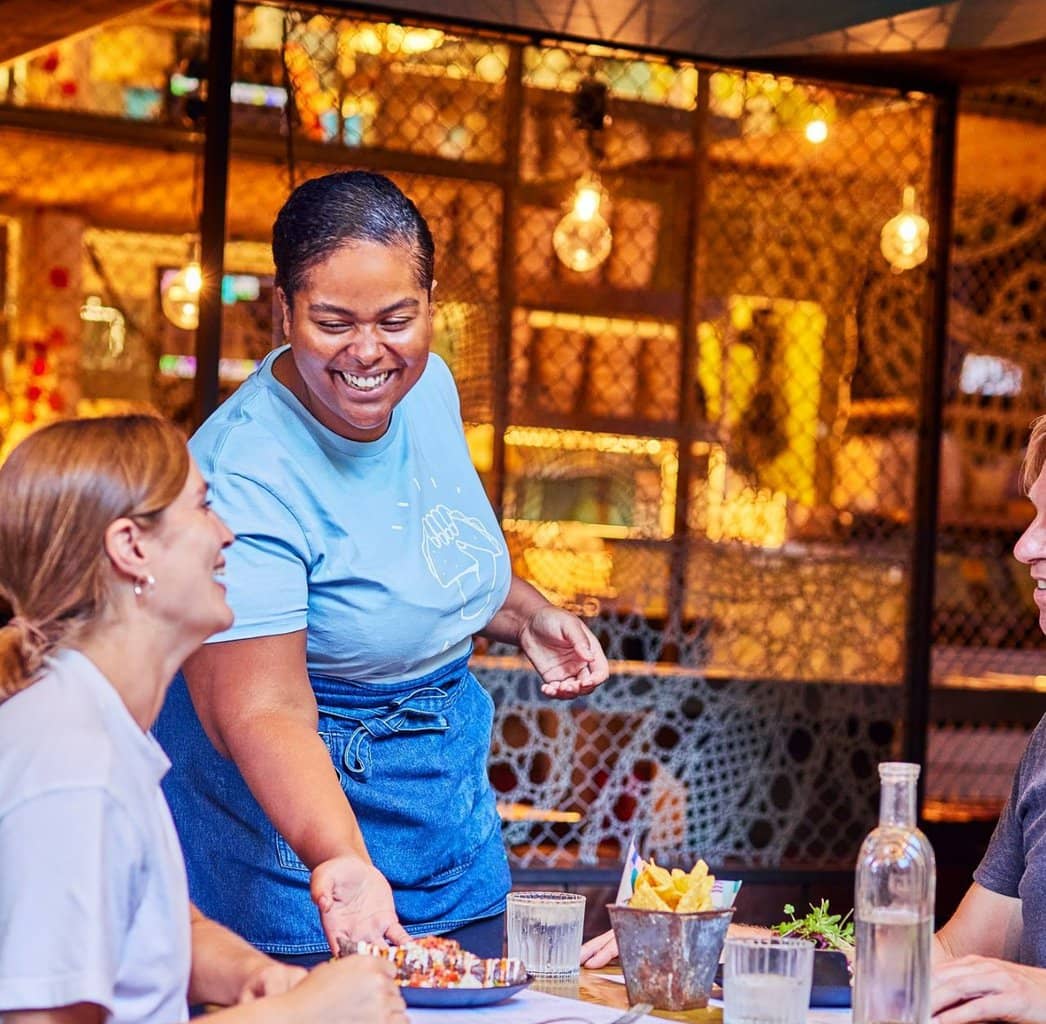 Waiter delivering a dish to a table at Wahaca