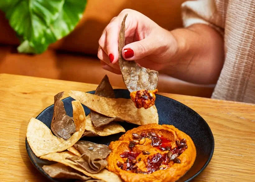 A tortilla chip scooping up our sonoran hummus