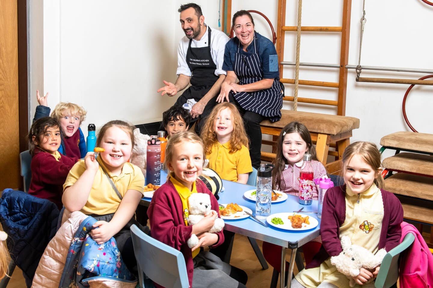 Chef and chef trainer from Chefs in schools with group of children sitting at a table with food