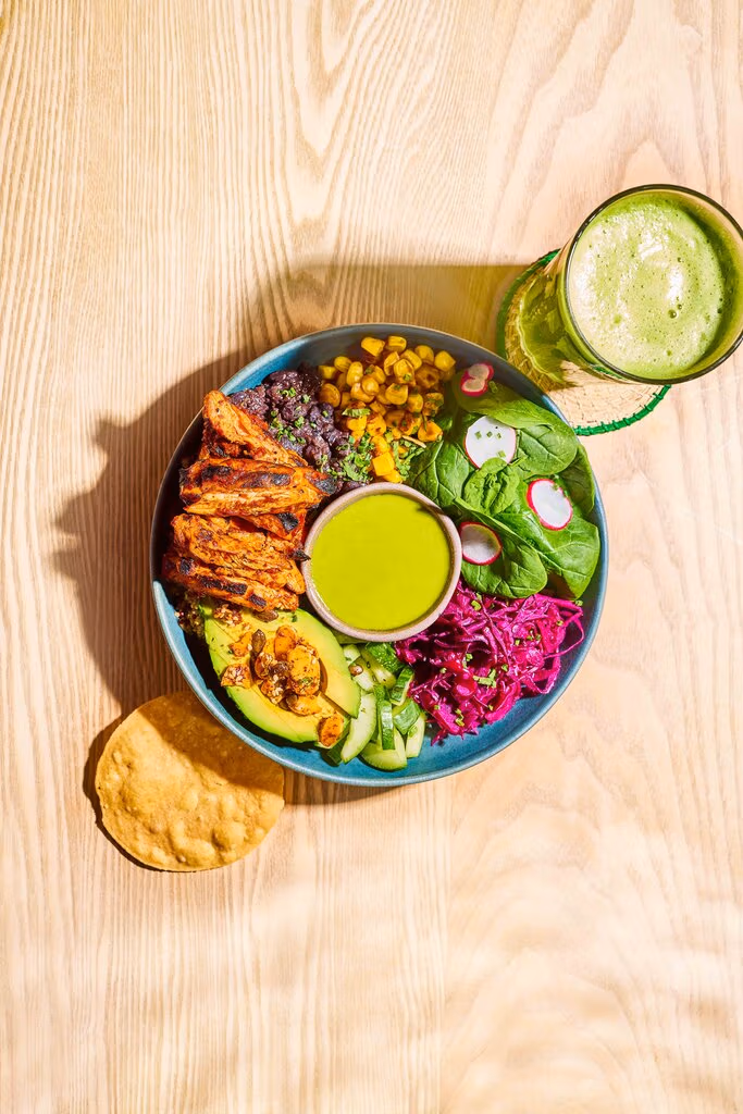 Sunshine bowl with 30 colourful plant based ingredients plus a protein of your choice. Zingy green dressing in the centre to pour over.