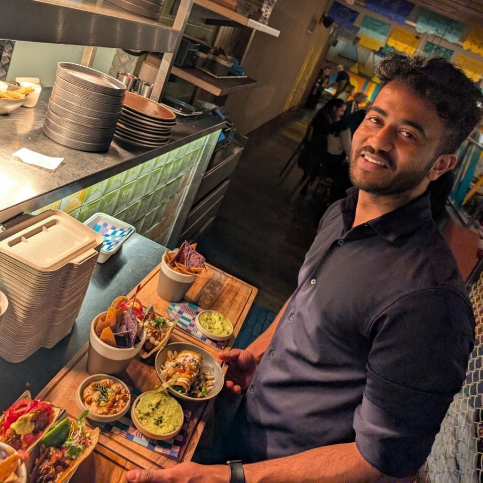 Front of house team member smiling at the pass with our freshly made dishes